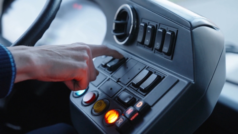 Ruka vozača pritiska dugmad na komandnoj tabli vozila tokom vožnje